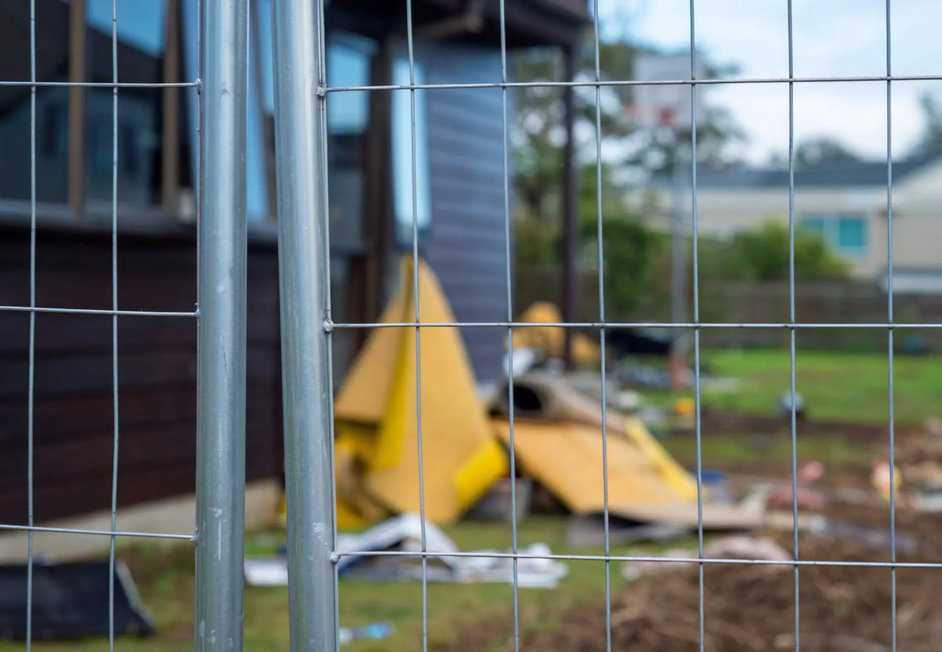 Temporary construction fencing protecting residential property under repair. Selective focus on fence. Temporary construction fencing protecting residential property under repair. Selective focus on fence.